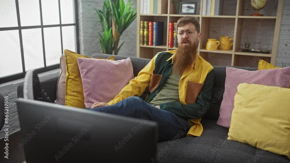 Bearded man relaxing on couch in modern living room with remote control and colorful pillows. Bearded man relaxing on couch in modern living room with remote control and colorful pillows.