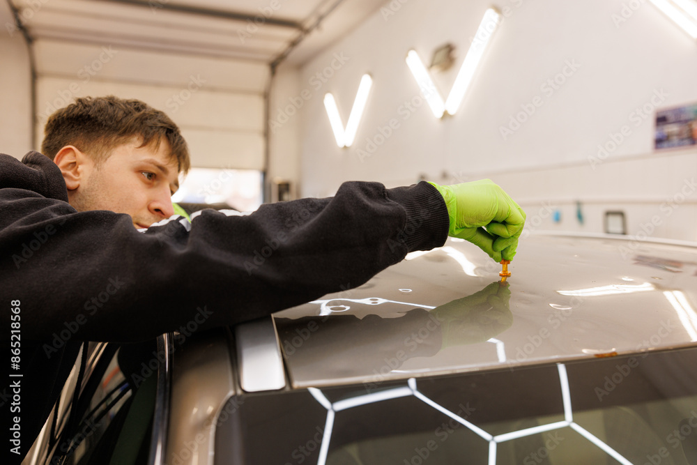 A professional car repair technician working on a vehicle in a garage with focus and precision