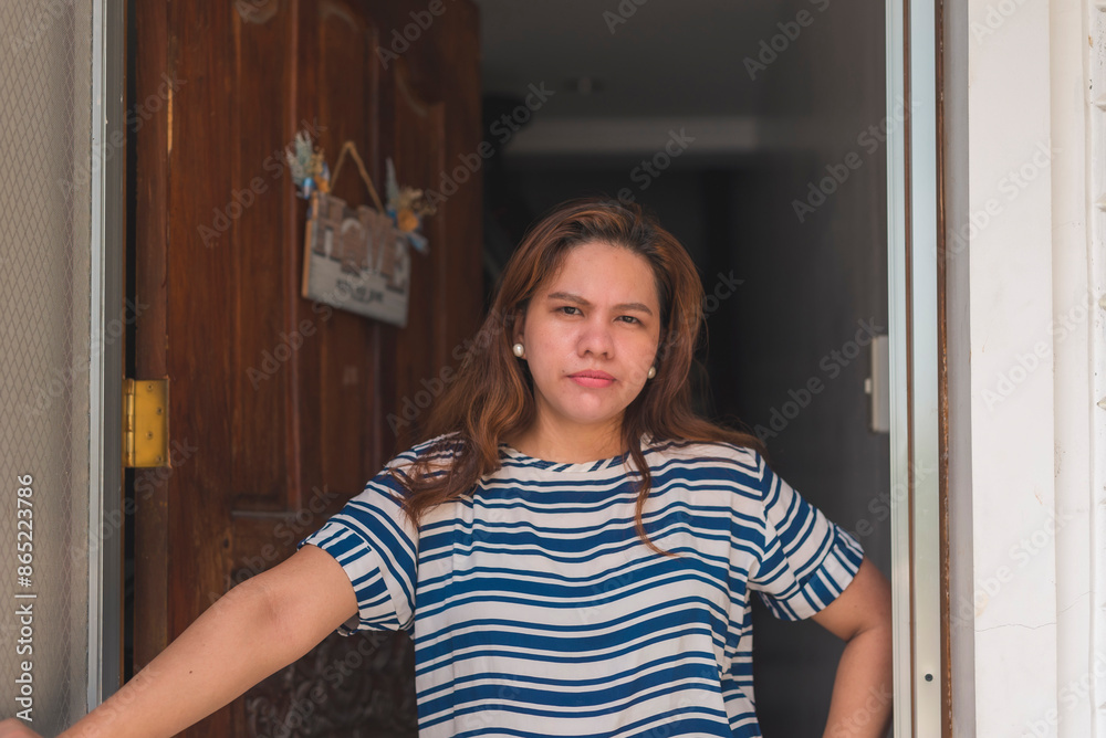 Asian woman in her 30s standing in a doorway, looking at someone with suspicion. Casual setting. Asian woman in her 30s standing in a doorway, looking at someone with suspicion. Casual setting.