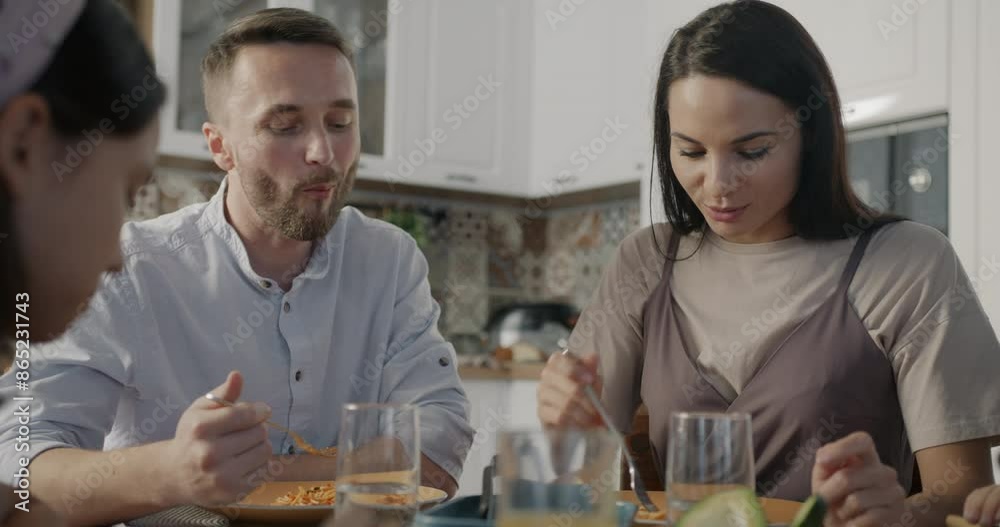 Man and woman married couple having lunch with daughter eating pasta and talking sitting around kitchen table together. People and family lifestyle concept. Man and woman married couple having lunch with daughter eating pasta and talking sitting around kitchen table together. People and family lifestyle concept.