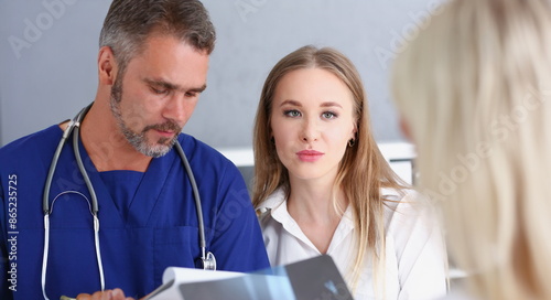 Konstfotografi Smiling handsome doctor communicate with patient holding silver pen and showing pad