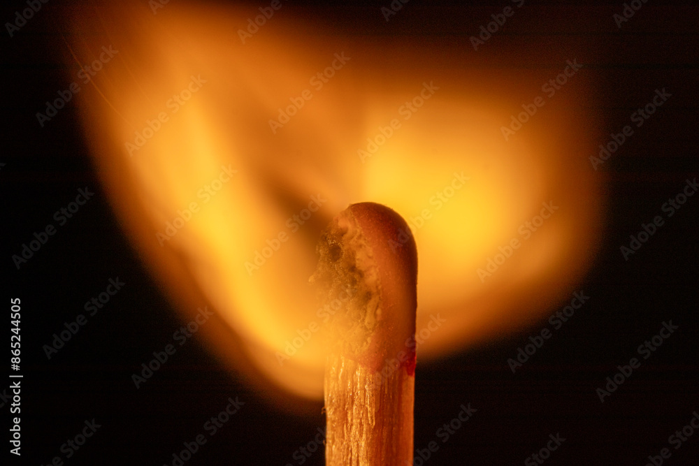Photograph of a matchstick with a fire burning. There is a black background. Photograph of a matchstick with a fire burning. There is a black background.