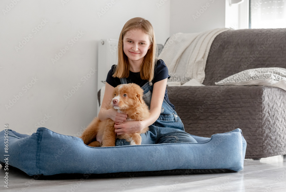 Small Girl With Toller Puppy Sits In Blue Dog Bed, Nova Scotia Duck Tolling Retriever Small Girl With Toller Puppy Sits In Blue Dog Bed, Nova Scotia Duck Tolling Retriever