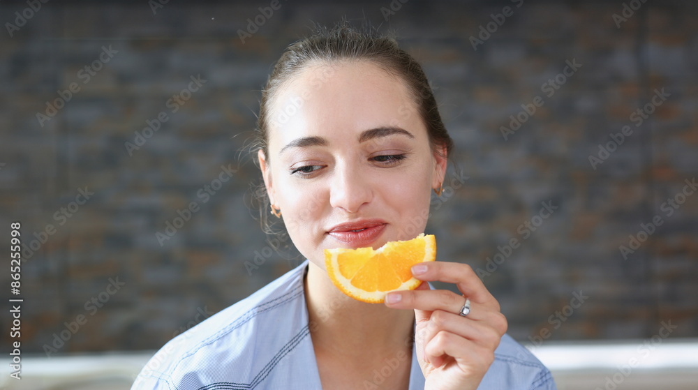 Beautiful brunette smiling woman eat sliced raw tasty orange half at kitchen in the morning portrait. Weight loss beauty fit concept Beautiful brunette smiling woman eat sliced raw tasty orange half at kitchen in the morning portrait. Weight loss beauty fit concept