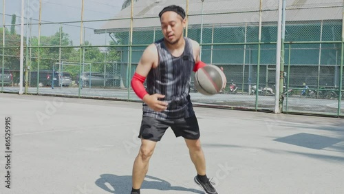 Young Asian Male Basketball Player Practicing And Showing Individual Skill Of Handling Ball On Court