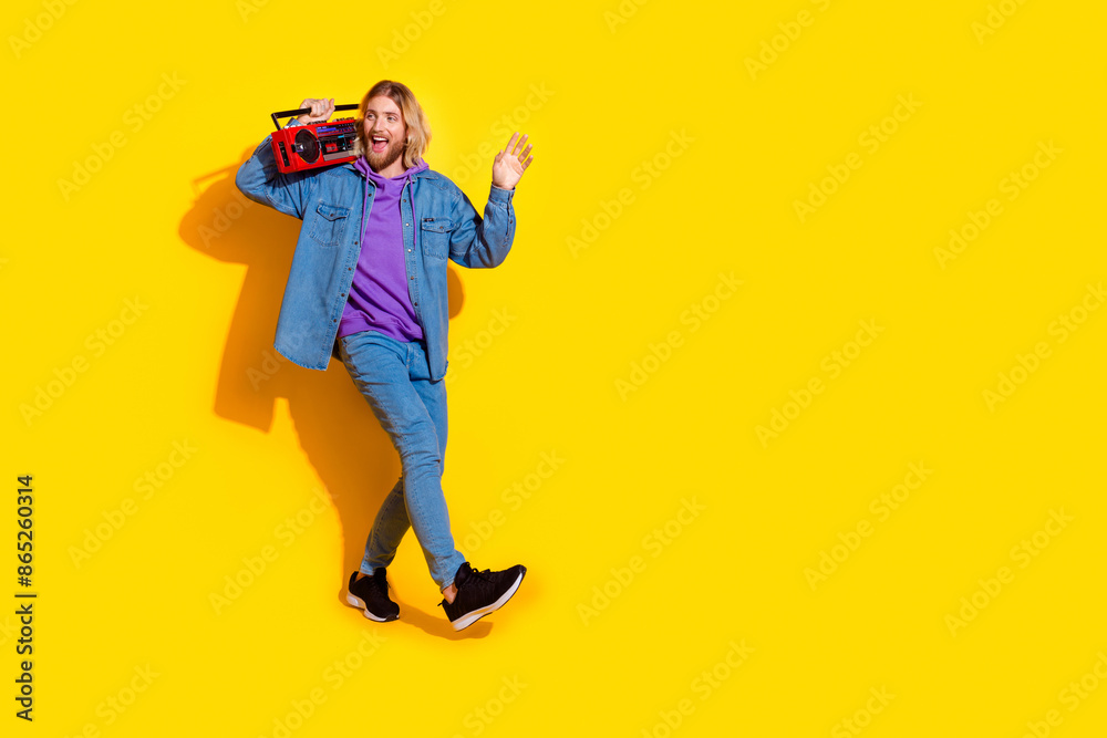 Full length portrait of nice young man boombox empty space wear denim jacket isolated on yellow color background Full length portrait of nice young man boombox empty space wear denim jacket isolated on yellow color background