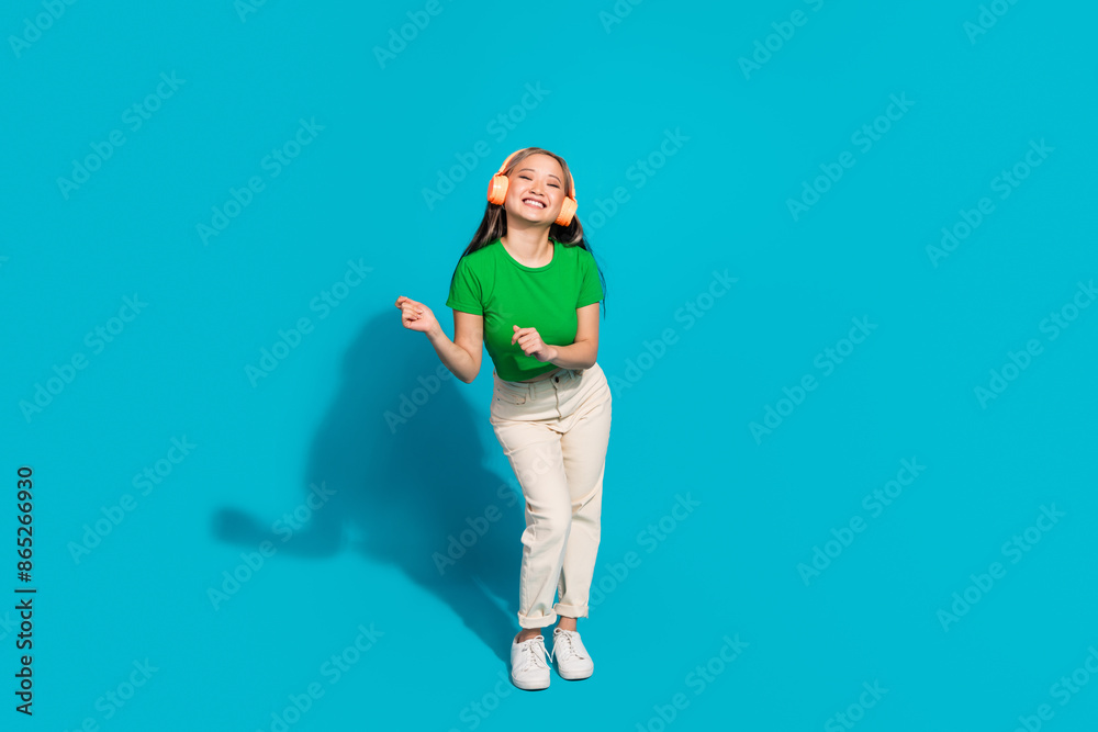 Full size photo of nice young girl headphones empty space wear t-shirt isolated on teal color background Full size photo of nice young girl headphones empty space wear t-shirt isolated on teal color background