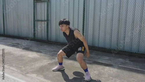 Young Asian Man Basketball Player Practicing Dribbling Skill By Bouncing Ball From Behind His Back