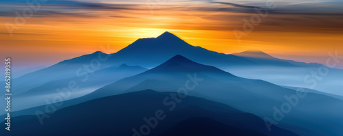 The mountains are covered in a blue mist and the sun is setting behind them