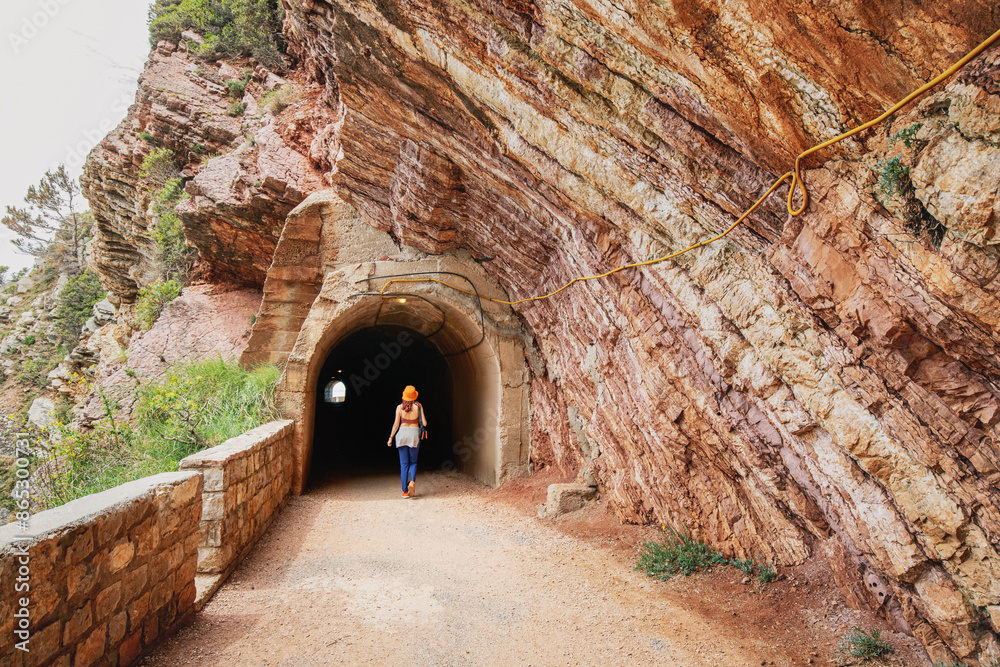 Obraz premium Traveler exploring a mountain track with a tunnel entrance on the coastline of Petrovac, Montenegro