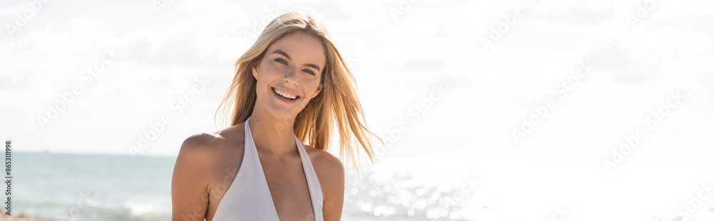 A young beautiful blonde woman in a white bikini stands gracefully on Miami Beach, symbolizing peace and serenity. A young beautiful blonde woman in a white bikini stands gracefully on Miami Beach, symbolizing peace and serenity.
