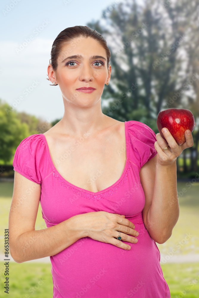 Pregnant woman gently cradles an apple while smiling directly at the camera, radiating maternal happiness and health Pregnant woman gently cradles an apple while smiling directly at the camera, radiating maternal happiness and health
