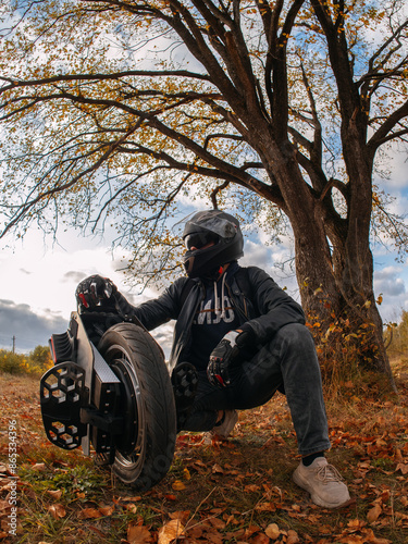 A man in a helmet is holding a monocycle. Electric monowheel is a modern urban transport. Riding in the autumn park photo