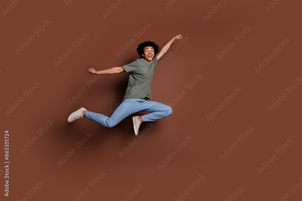 Full size photo of nice young guy flying superhero wear trendy khaki outfit isolated on brown color background Full size photo of nice young guy flying superhero wear trendy khaki outfit isolated on brown color background