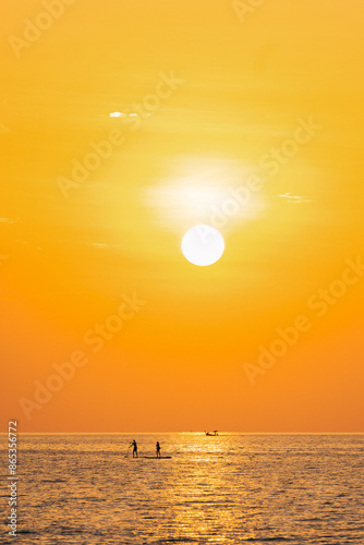 Obraz na płótnie Stunning view of two people standing up on a SUP during a breathtaking sunset in Thailand. w salonie