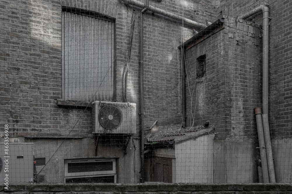 Gritty back yard, grey scale, grimy walls old air conditioner, bird mesh. Gritty back yard, grey scale, grimy walls old air conditioner, bird mesh.