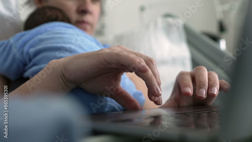 Hands of new mother browsing internet on laptop while holding sleeping newborn baby, multitasking in hospital bed, combining parenting and work, postnatal care