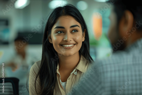 Smiling Professional Indian Woman Engaging in Conversation with Colleague in Office © Ignats