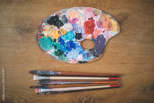 Artist's palette and paintbrushes on wooden background