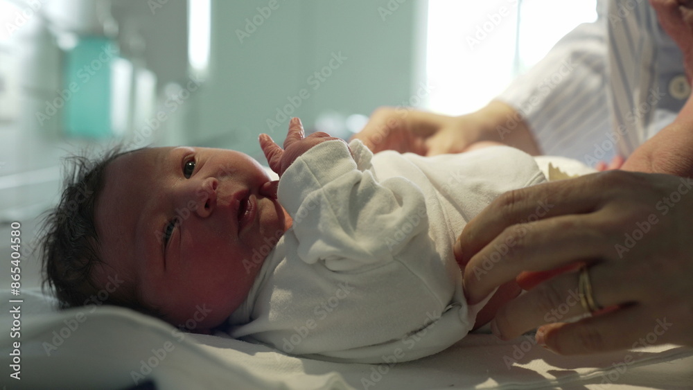 Obraz premium Newborn baby being gently dressed in a white onesie by caring hands in a hospital, showcasing the delicate and tender care given to newborns immediately after birth in a medical setting