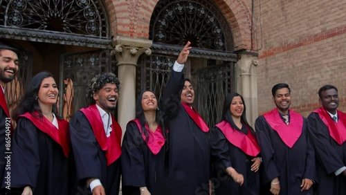 Graduating Indian students throwing graduation caps in the air. Friends wearing traditional academic gown, cap, celebrate academic achievement.