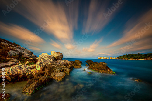 Dramatic Coastal Sunset Over Rocky Shoreline. A breathtaking coastal scene at sunset, featuring dramatic, streaked clouds, and a calm, turquoise sea. Sile, Kandira, Kerpe, Kefken. photo