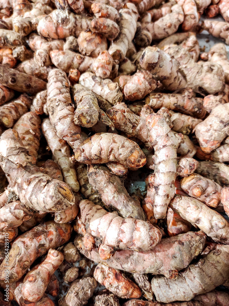 A stack of turmeric or kunyit, a traditional spice commonly used in Asian, especially Southeast Asian, cuisine, displayed in a traditional market stall A stack of turmeric or kunyit, a traditional spice commonly used in Asian, especially Southeast Asian, cuisine, displayed in a traditional market stall