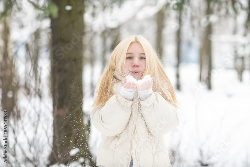 Portrait of a young beautiful blonde girl outdoors in winter in cloudy weather.