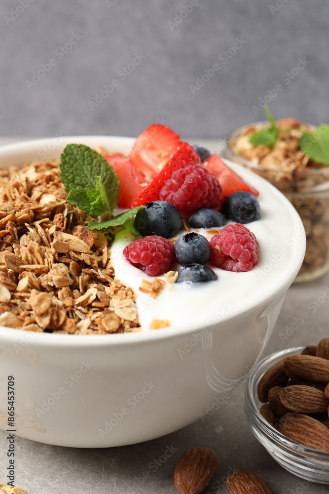 Tasty granola with berries and yogurt in bowl on grey table, closeup Tasty granola with berries and yogurt in bowl on grey table, closeup