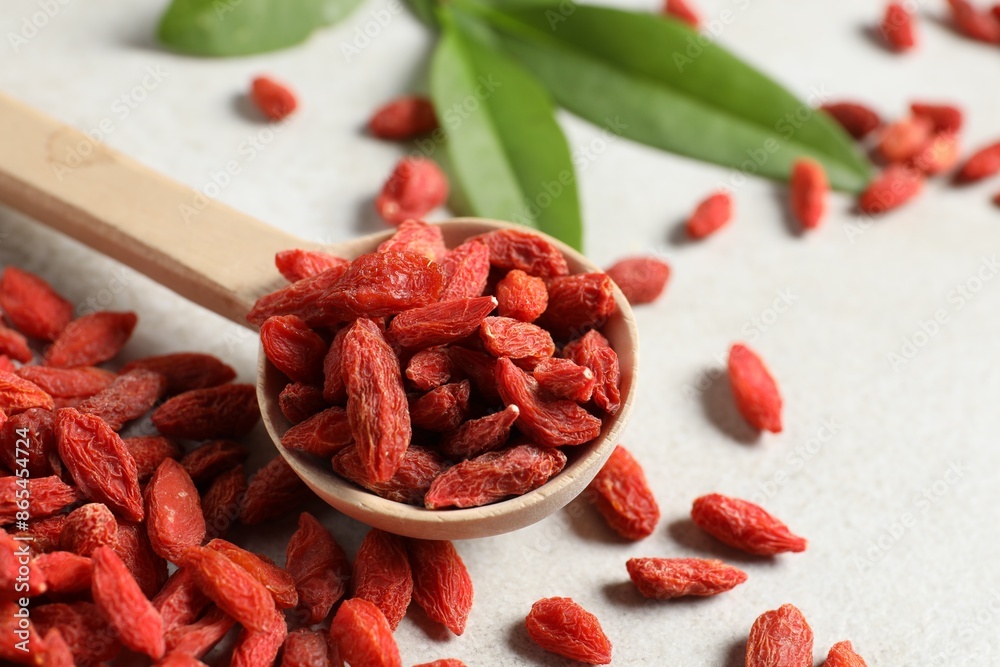 Dried goji berries and spoon on light table, closeup Dried goji berries and spoon on light table, closeup