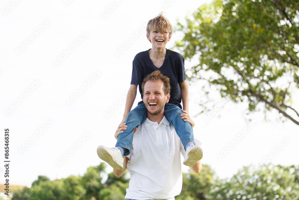Man piggyback his son on a shoulder and walking around the park. Man piggyback his son on a shoulder and walking around the park.