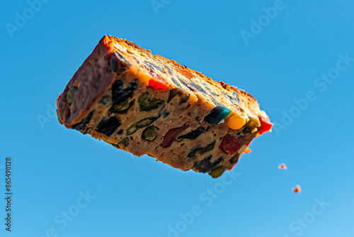 Close-up action shot of a fruitcake mid-air, flying against a clear blue sky, capturing the whimsical and festive spirit of Fruitcake Toss Day photo