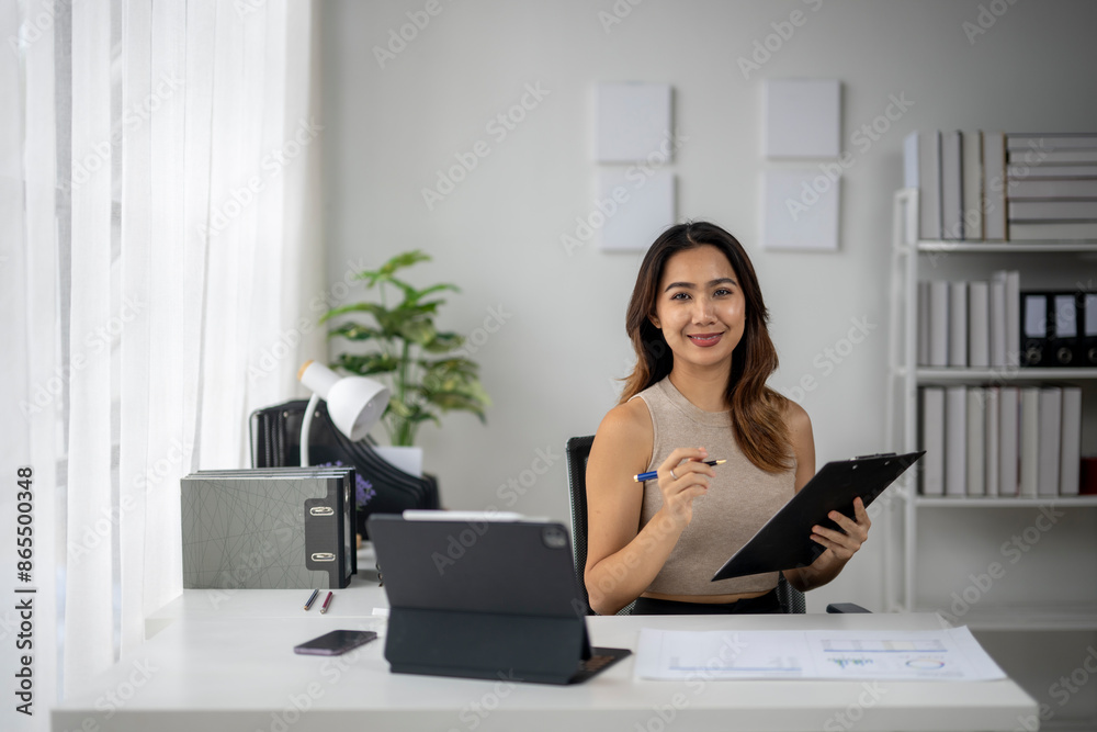 A woman is sitting at a desk with a clipboard and a pen A woman is sitting at a desk with a clipboard and a pen