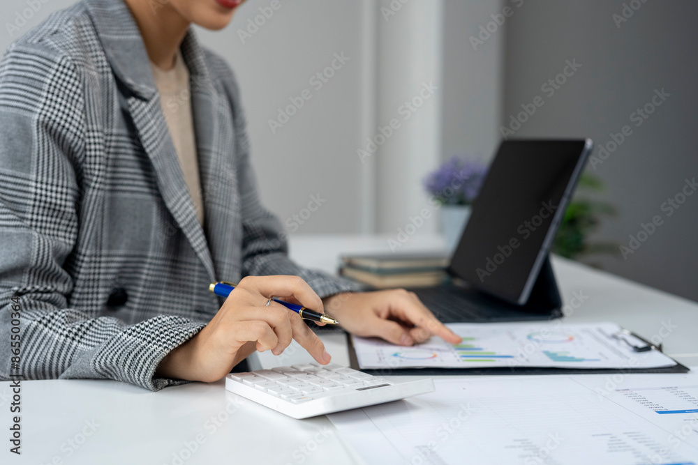 A woman is sitting at a desk with a laptop and a calculator A woman is sitting at a desk with a laptop and a calculator