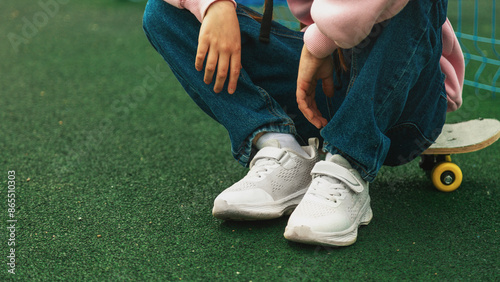 child skater, kid girl sitting relax at skatepark with skateboard. extreme sports in skate park