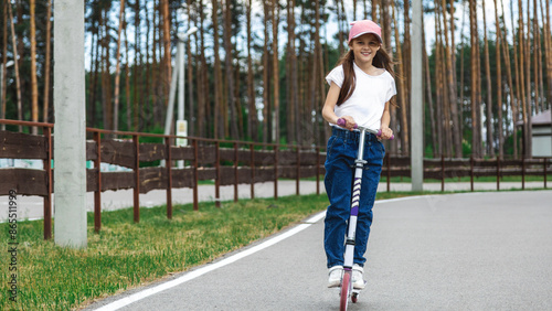 Little girl riding scooter. Kids ride kick board. Child playing on suburban street on sunny summer day. Healthy outdoor activity. Cute kid on his way to school.