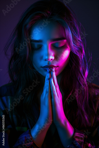 Woman praying and contemplating. Peace of mind concept. Thankfulness. Unique neon fantasy ethereal background. Portrait of Teen girl in prayer. Maitri - Friendship or loving-kindness. photo