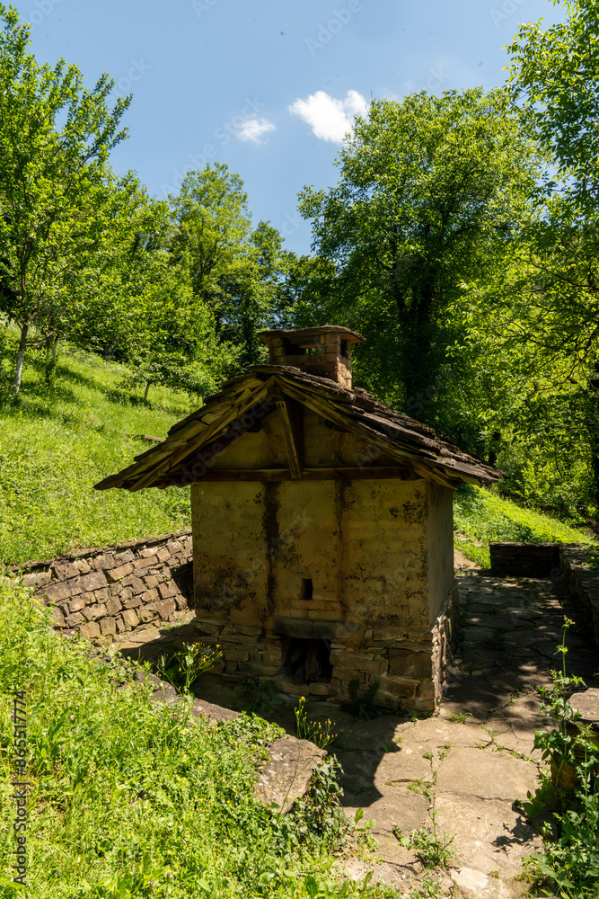 Old watermill building standing on a hillside surrounded by lush green forest Old watermill building standing on a hillside surrounded by lush green forest