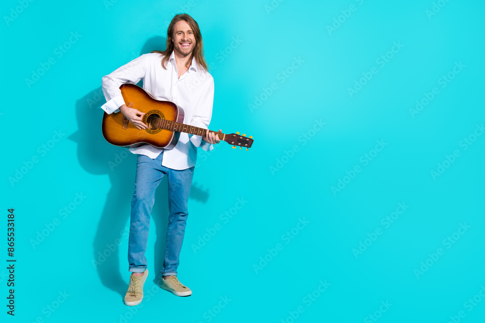 Full length photo of handsome good mood guy wear white shirt playing guitar emtpy space isolated blue color background Full length photo of handsome good mood guy wear white shirt playing guitar emtpy space isolated blue color background