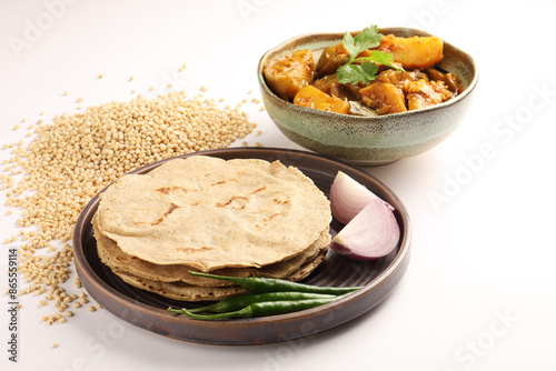 Egg plant and Potato curry bhakri or Indian flat bread served with green chilli chutney traditionally called as Theccha in Marathi and  onion beside the plate

  photo