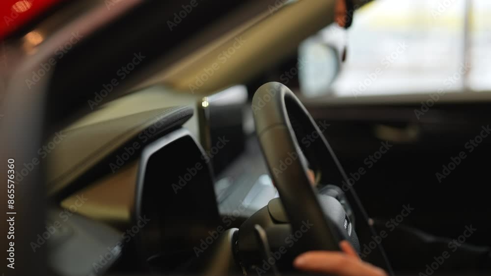 Closeup hands of unrecognizable female customer testing new car at dealership, holding steering wheel. Close-up cropped shot of young woman examining automobile in auto dealership, slow motion. Closeup hands of unrecognizable female customer testing new car at dealership, holding steering wheel. Close-up cropped shot of young woman examining automobile in auto dealership, slow motion.