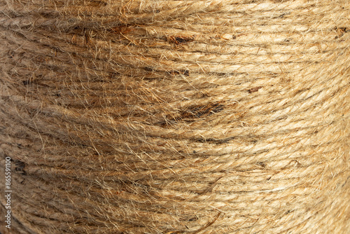 Close-up image of a natural jute twine spool, showcasing the rough, fibrous texture. The organic quality and intricate weave reveal the intertwined strands and fibers, highlighting the rope’s strength