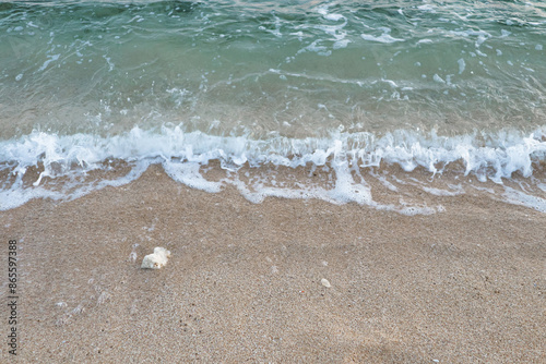 Defocused close-up soft wave of the sea on the sandy beach.