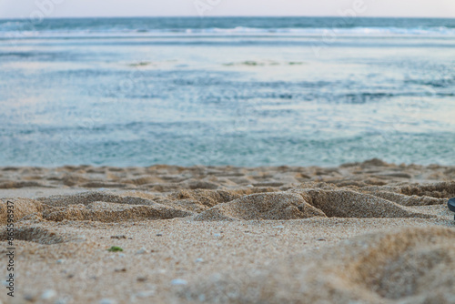 Seascape abstract beach background. blur bokeh light of calm sea and sky. Focus on sand foreground.