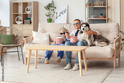 Mature doctor with his little son and dog watching TV at home