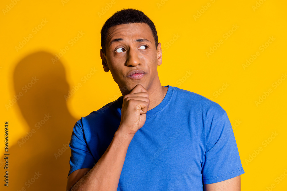 Photo portrait of attractive young man look skeptical empty space think dressed stylish blue clothes isolated on yellow color background Photo portrait of attractive young man look skeptical empty space think dressed stylish blue clothes isolated on yellow color background