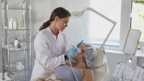 Female doctor making facial beauty procedure with macro molecule atomizing pen to female patient. High quality 4k footage photo