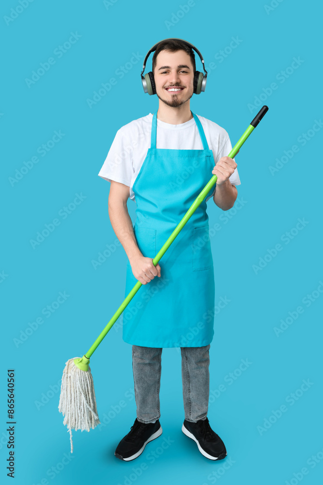 Male janitor with mop and headphones on blue background Male janitor with mop and headphones on blue background