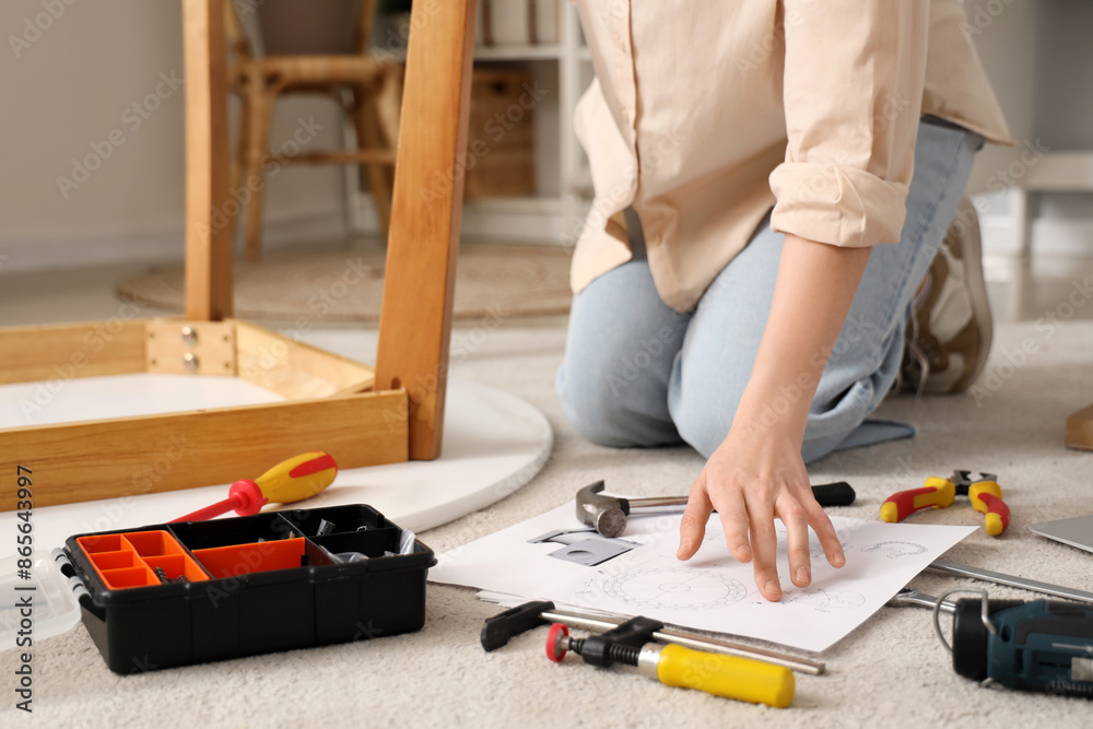 Beautiful young woman with manual and tools assembling table at home, closeup Beautiful young woman with manual and tools assembling table at home, closeup