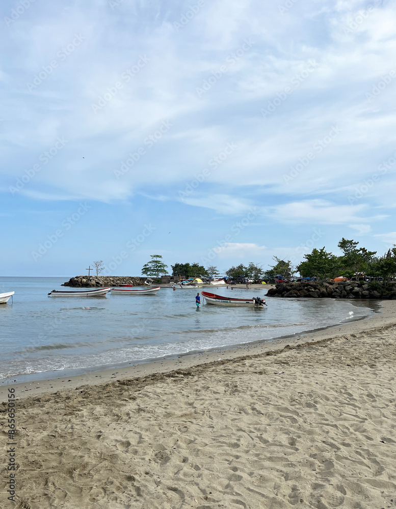 Beautiful beach and tropical sea, dreamy sky under the sunlight, small fishing boat next to rocks and vegetation Beautiful beach and tropical sea, dreamy sky under the sunlight, small fishing boat next to rocks and vegetation